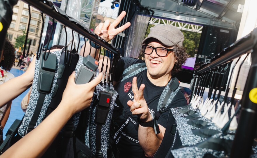 Daniel Belquer of Music: Not Impossible poses for a photo while organizing a rack of haptic suits at the Silent Disco dance party at Lincoln Center, New York City on Saturday, July 1, 2023.