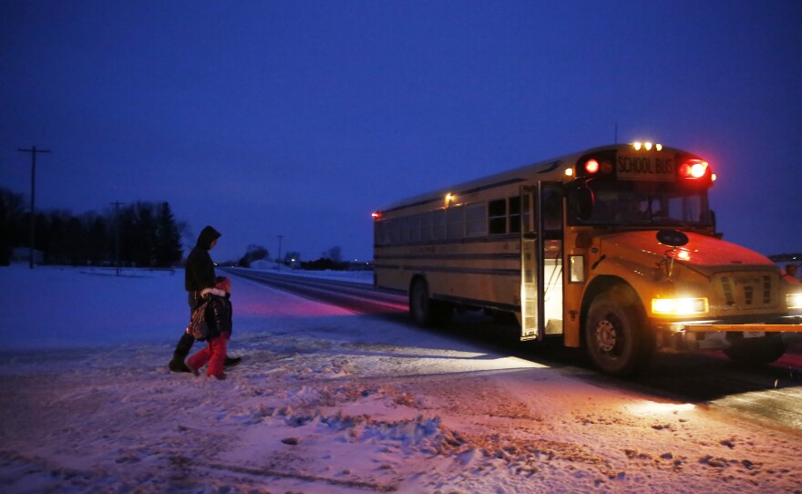 Ryan walks his older daughter, Kading, to her school bus at the end of the driveway.