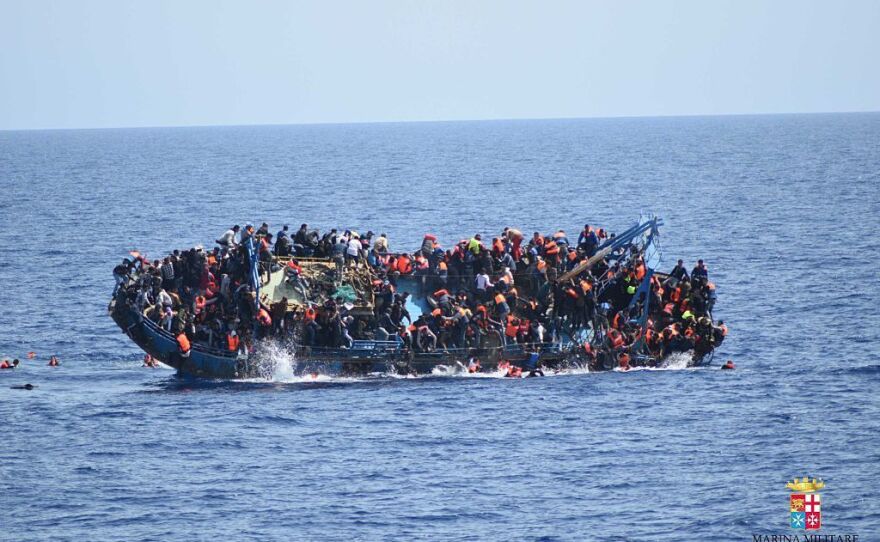 Migrants in an overcrowded boat, which was about to capsize, are rescued by Bettica and Bergamini ships of Italian Navy at Sicilian Strait, between Libya and Italy, in Mediterranean sea on Wednesday.