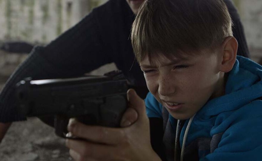 Oleg with a gun. Follow the life of 10-year-old Ukrainian boy Oleg over a year and witness the gradual erosion of his innocence beneath the pressures of the ongoing war in Eastern Ukraine.