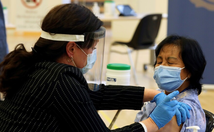 A health care worker administers a Pfizer-BioNTech COVID-19 vaccine to personal support worker Anita Quidangen at The Michener Institute, in Toronto, Canada, on Monday. Quidangen was one of the first people in Canada to receive the shot.
