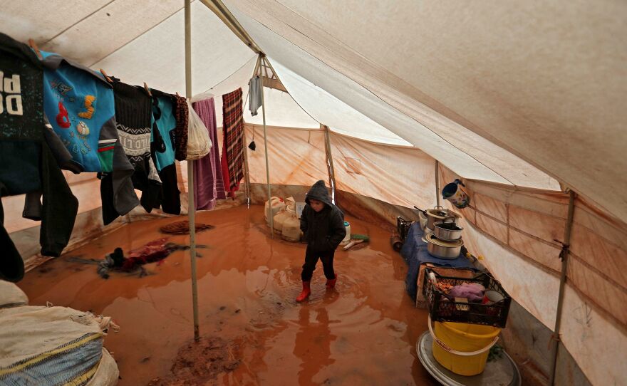 A child walks inside a flooded tent at a camp for the displaced people near Bab al-Hawa by the border with Turkey, in Syria's northwestern Idlib province, on Monday.