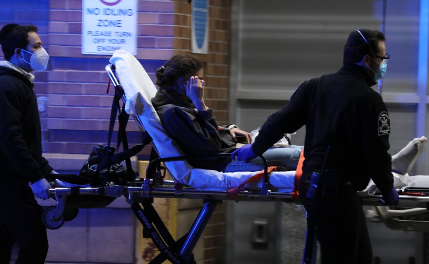 Medical workers take in patients outside a coronavirus intake area at Maimonides Medical Center in Brooklyn, New York.