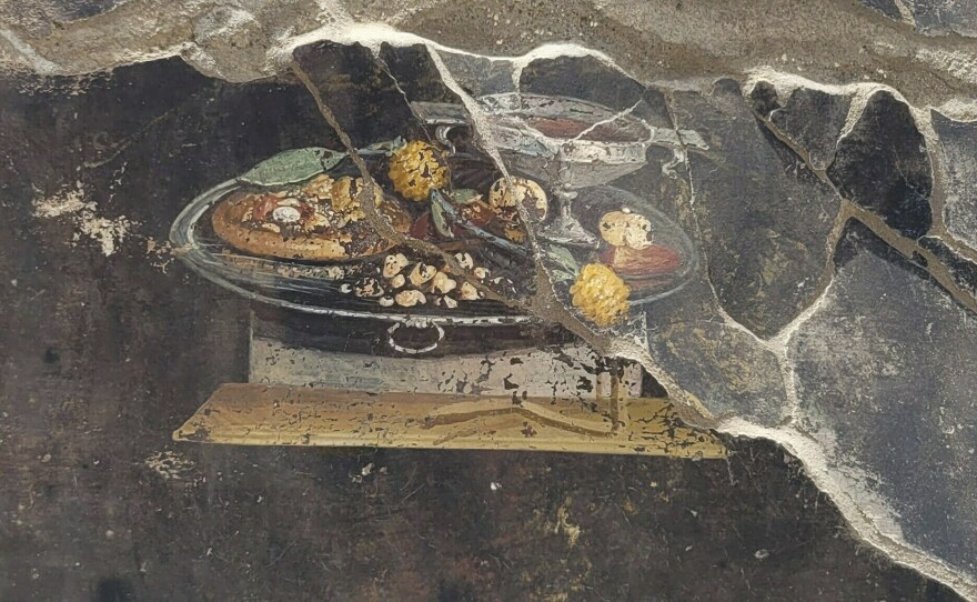 This picture provided on Tuesday, June 27, 2023, by the Pompeii Archaeological Park shows the wall of an ancient Pompeian house with a fresco depicting a table with food.