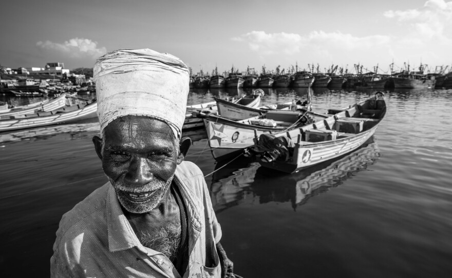 Pavadairayan, 60, a migrant laborer known as a "basket man," carries fish in a basket on his head from boats to the auction house at Kasimedu Fishing Harbour in Chennai, India.
