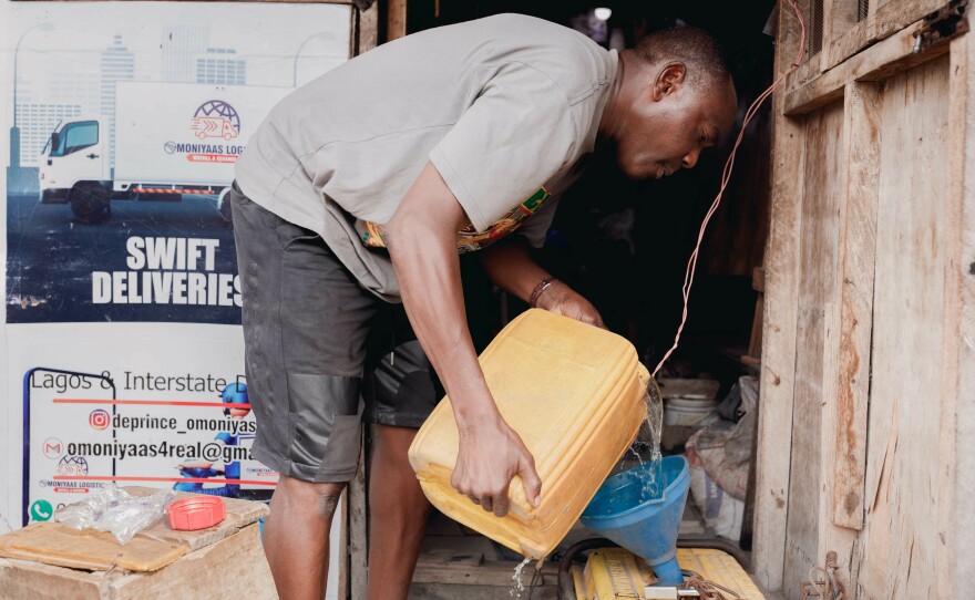 Beautician Kehinde Adebajo pours fuel into the generator in front of his salon. When the government ended its massive fuel subsidy in May, fuel prices quickly shot up.