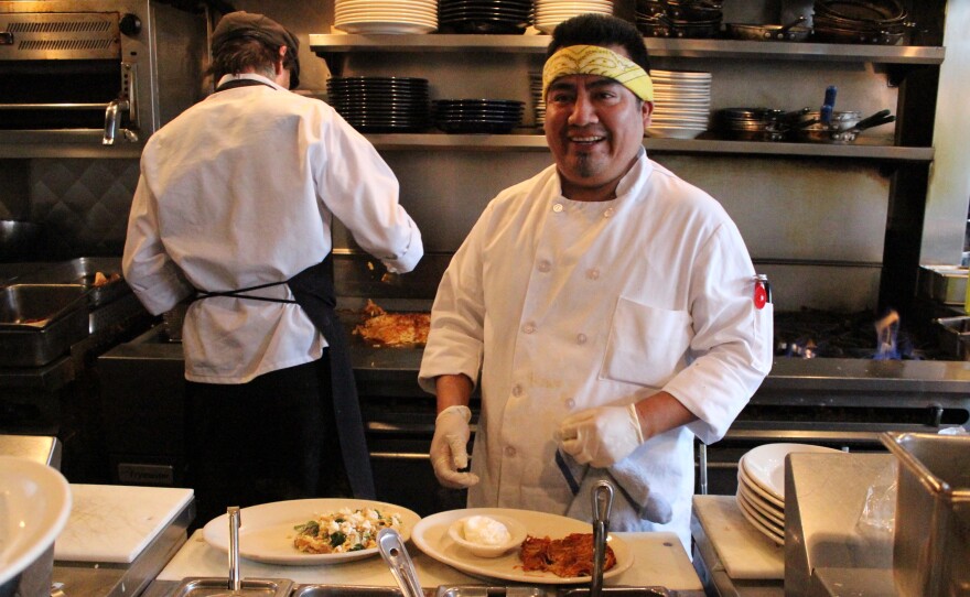 Carter Jorgensen, with head chef Zephyr Paquette in the background, at Seattle's Coastal Kitchen. The restaurant is trimming its hours in response to the city's new higher minimum wage.