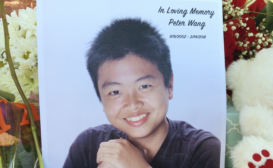 Peter Wang is seen in this photo near a memorial in Parkland, Fla., on Friday. Wang, a student at Marjory Stoneman Douglas High School in Parkland, Fla., was killed when former student Nikolas Cruz opened fire at the school on Wednesday, Feb. 14.