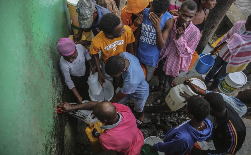 <strong>Sun., Aug. 15:</strong> People displaced by the earthquake collect water after sleeping in the streets in Les Cayes, Haiti.