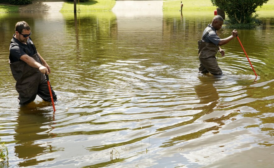 Hinds County Emergency Management Operations deputy director Tracy Funches, right, and operations coordinator Luke Chennault, wade through flood waters in northeast Jackson, Miss., Monday, Aug. 29, 2022.