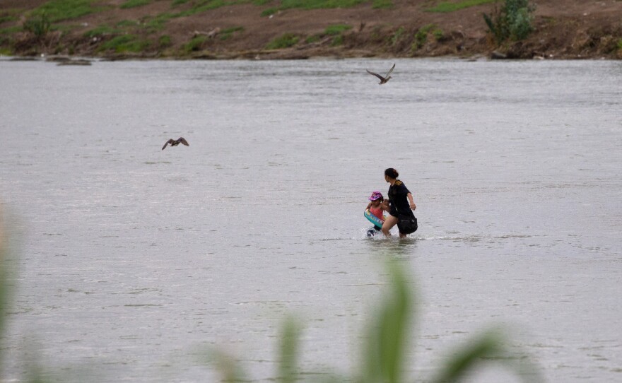 A woman and a child cross the Rio Grande river towards the U.S. in Eagle Pass, Texas, Sunday May 22, 2022. Little has changed in what has quickly become one of the busiest corridors for illegal border crossings since a federal judge blocked pandemic-related limits on seeking asylum from ending Monday.
