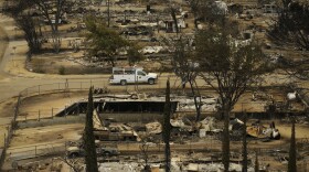 A pickup truck passes by the remains of mobile homes devastated by a wildfire in South Lake, Calif., June 25, 2016.
