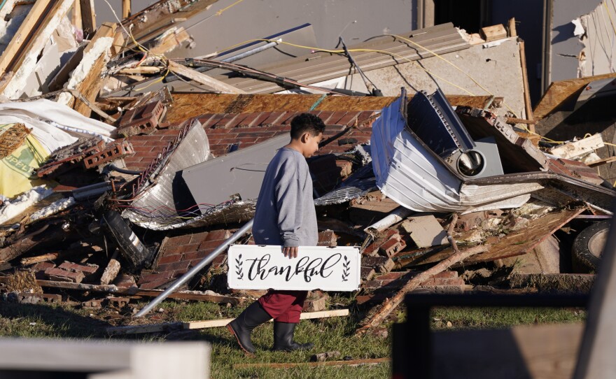 Logan Johnson, 11, carries a sign that reads "Thankful" after he recovered it from his family's destroyed home on Saturday after a tornado hit in Powderly, Texas.
