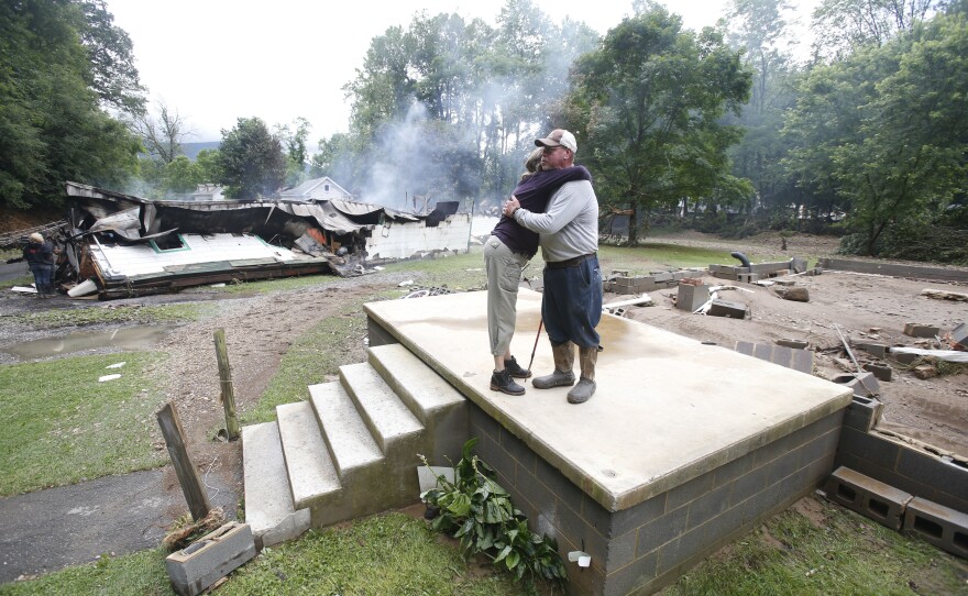 Jimmy Scott gets a hug from Anna May Watson (left) as they clean up from severe flooding in White Sulphur Springs, W. Va., on Friday.