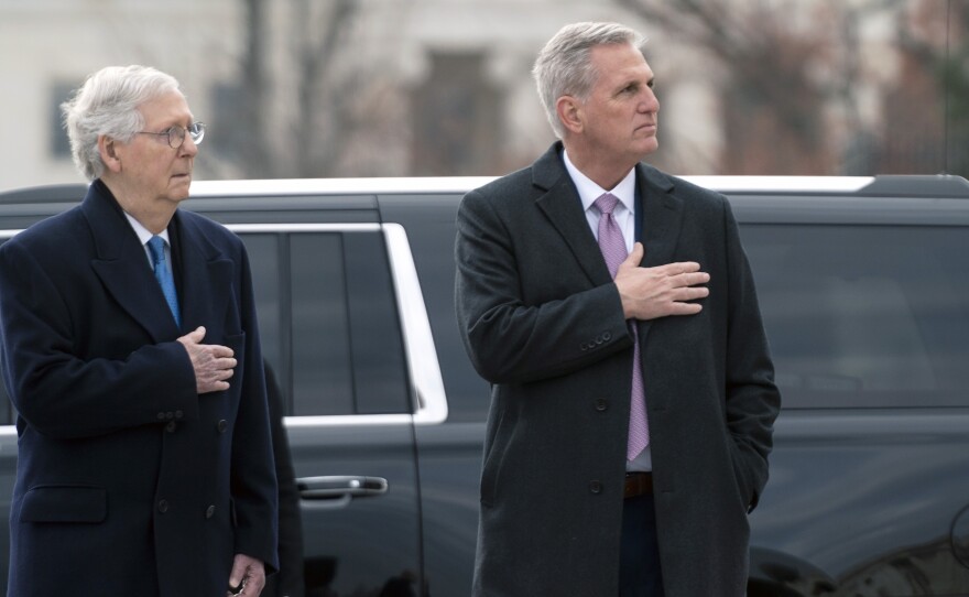 Senate Republican leader Mitch McConnell and House Republican leader Kevin McCarthy watch as a military honor guard carries the flag-draped casket of former Sen. Bob Dole from the U.S. Capitol on Dec. 10, 2021.