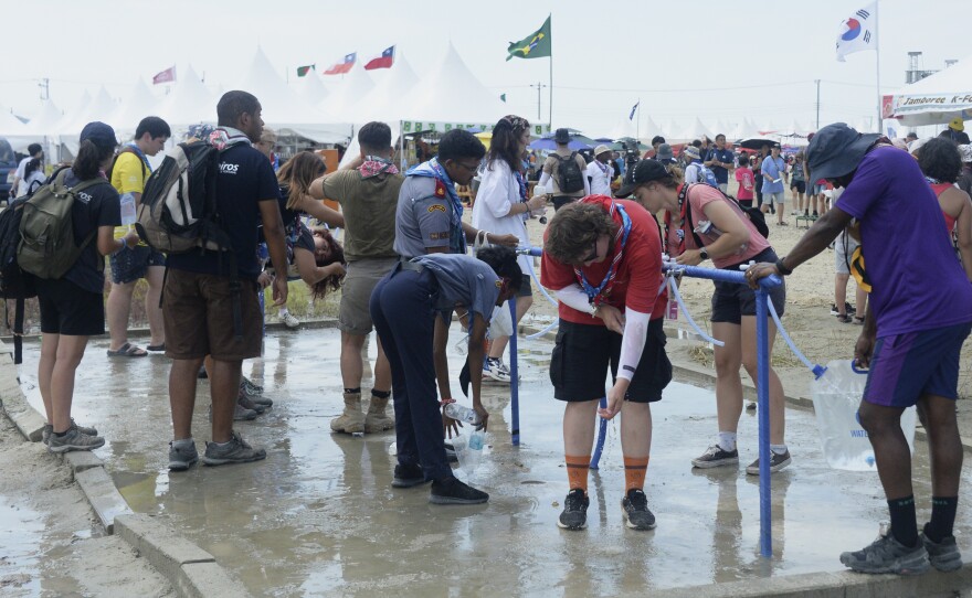 Attendees of the World Scout Jamboree cool off with water at a scout camping site in Buan, South Korea, on Friday.