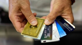 Alain Filiz shows off some of his credit cards as he pays for items at Lorenzo's Italian Market on May 20, 2009 in Miami, Florida.