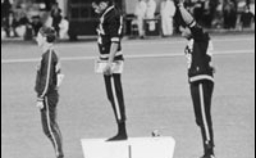 American track and field athletes Tommie Smith (center) and John Carlos (right) protest with the Black Power salute as they stand on the winner's podium at the 1968 Summer Olympic Games in Mexico City.