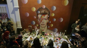 People gather next to tributes placed near a mural of British singer David Bowie by artist Jimmy C, in Brixton, south London, Jan. 11, 2016. Bowie, who broke pop and rock boundaries with his creative musicianship, nonconformity, striking visuals and a genre-spanning persona he christened Ziggy Stardust, died of cancer on Sunday. Bowie, 69, was born in Brixton.