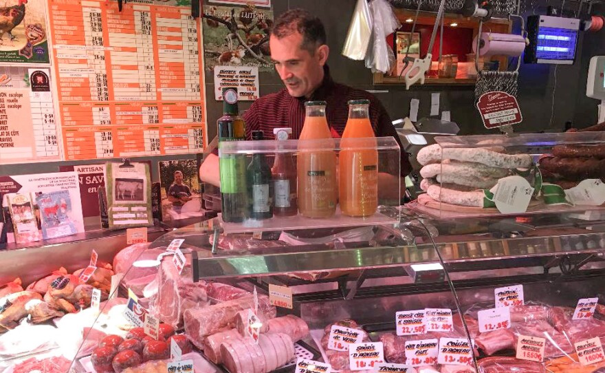 Didier Tass, behind the counter of his butcher shop, says he purchases meat from small farmers who raise cows and butcher them humanely and in small quantities.