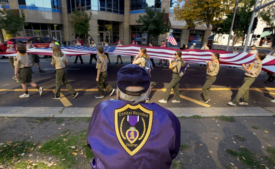 Army veteran Andy Zoglman, 77, watches an American flag pass by during a Veterans Day parade in Sacramento, on Nov. 11, 2023.