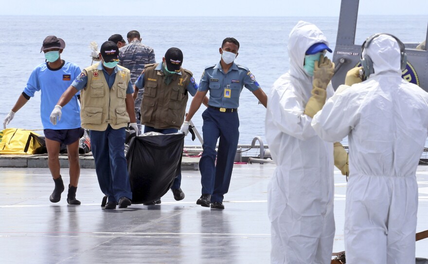Crew members carry a bag containing the body believed to be a victim of AirAsia Flight 8501 to a waiting helicopter on the deck of Indonesian Navy ship KRI Banda Aceh, on the Java Sea, Indonesia, on Friday.