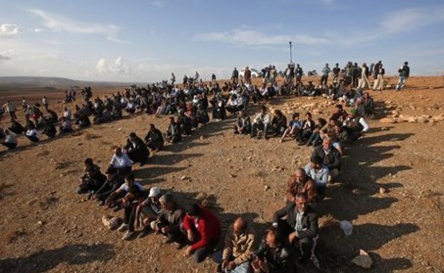 Kurds sit in formation to form the initials of the People's Protection Unit, or YPG, the main Kurdish militia in Syria, on a hilltop overlooking Kobani just over the border, in support of Syrian Kurds fighting ISIS, on Wednesday. Turkey believes the People's Protection Unit have ties to a Kurdish group in Turkey that is the Turkish government considers a terrorist organization.
