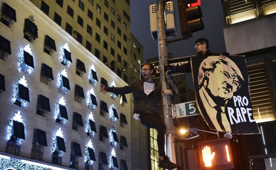 Protesters shout slogans from a lamppost during in a demonstration on Fifth Avenue across from Trump Tower on Wednesday, after Donald Trump was elected to be the next president of the U.S.