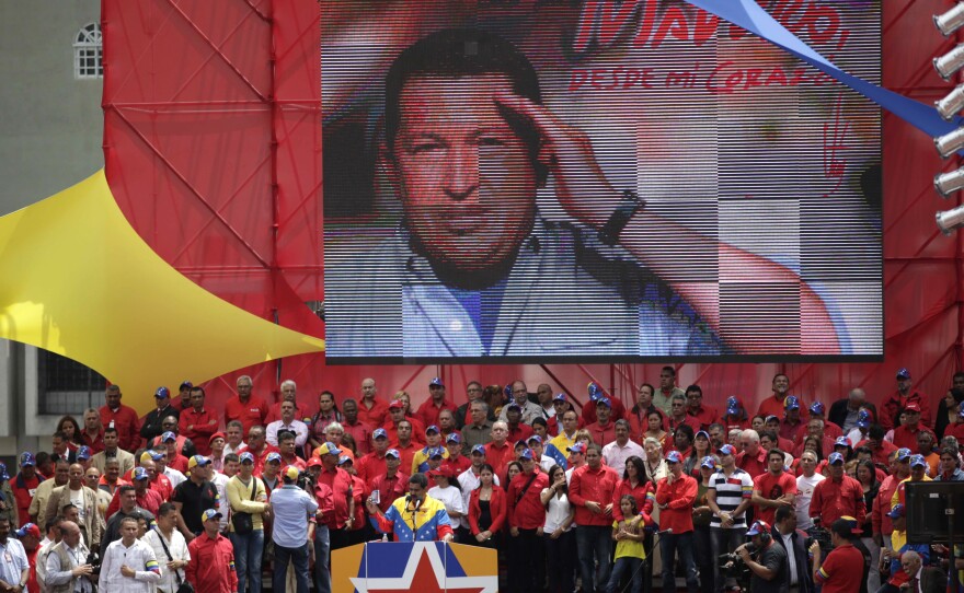 An image of late President Hugo Chavez hangs behind acting President Nicolas Maduro, as he speaks to supporters after registering his candidacy outside the national electoral council in Caracas, Venezuela, on Monday.