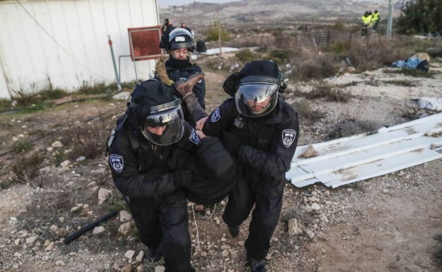 Israeli security forces carry away a settler as they evacuate hard-line residents from the Amona outpost in the West Bank on Wednesday.