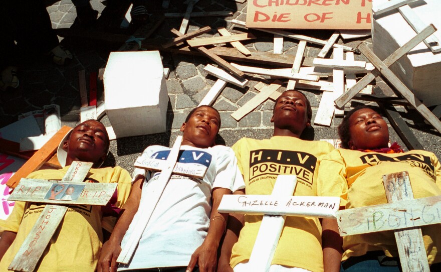 Four youths lay on the ground surrounded by crosses symbolizing victims of HIV-AIDS in a demonstration on November 26, 2001 in Cape Town, South Africa. The protest was aimed at the government's AIDS policies, including a failure to distribute antiretroviral drugs to pregnant mothers.