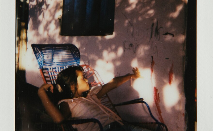 Anyelis, age 7, plays with the light outside of her home.