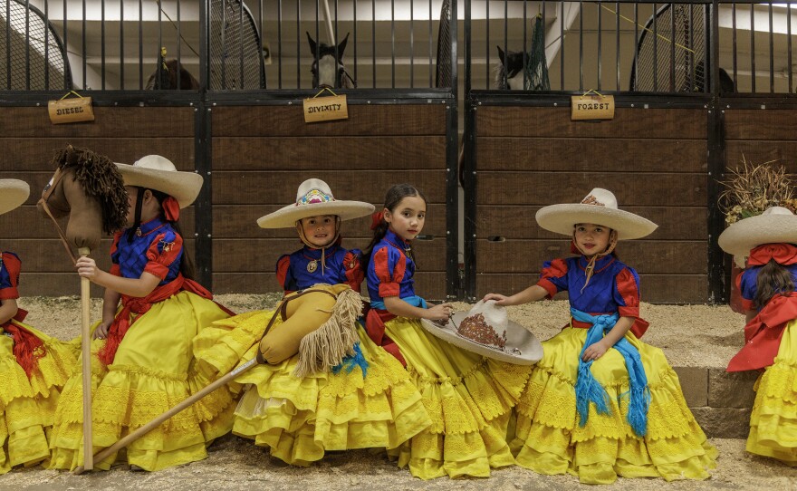 Sophia Barragan, Bethany Diaz and Isabel Moreno Jacobo, members of the Escaramuzitas Adelitas de Colorado, pose for a photo while they wait to perform with the stick horses at the National Western Stock Show's Mexican Rodeo Extravaganza.