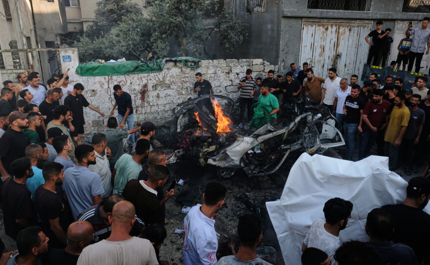 Palestinians gather around a car struck in an Israeli military strike in Gaza City, Sunday, Aug. 2, 2026.