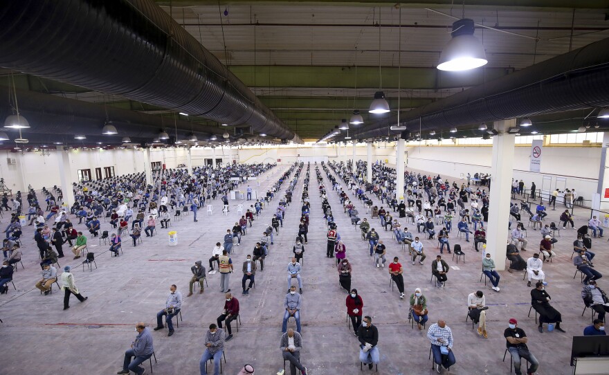 Guest workers from Egypt, Lebanon and Syria wait to be screened for COVID-19 after arriving in Kuwait. The photo was taken in Kuwait City on March 16, 2020.