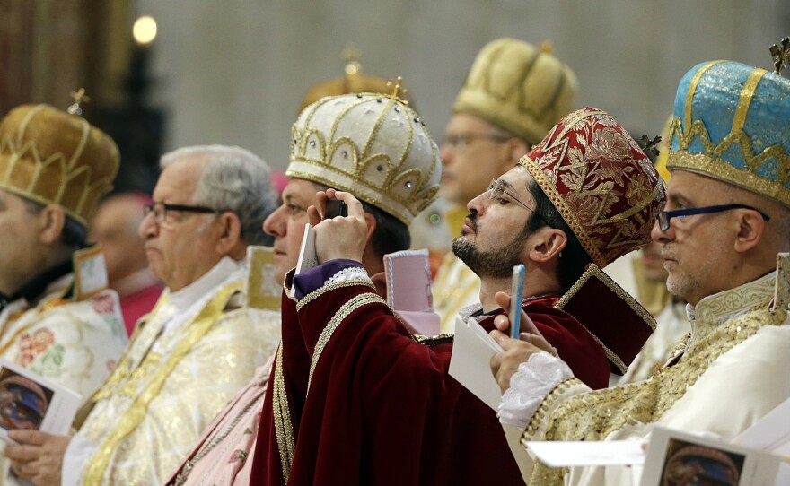 Prelates take pictures as Pope Francis celebrates an Armenian-Rite Mass to commemorate the 100th anniversary of the Armenian Genocide, in St. Peter's Basilica, at the Vatican Sunday.