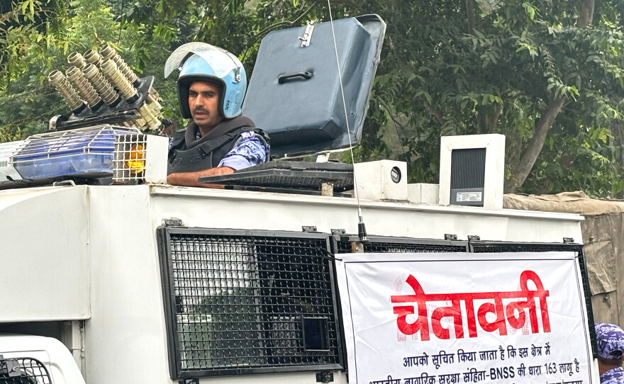 An armored vehicle with a banner warning citizens against unlawful gathering stands near the venue of a youth protest demanding the resignation of the country's election chief Gyanesh Kumar, in New Delhi, India, Saturday, Oct. 10, 2026. (AP Photo/Manish Swarup)
