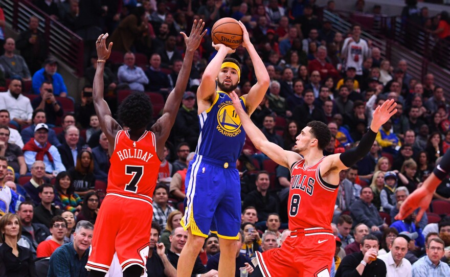 Golden State Warriors guard Klay Thompson shoots the ball against Chicago Bulls forward Justin Holiday (7) and guard Zach LaVine (8) during Monday night's game. Thompson broke the NBA's single-game record for 3-pointers.