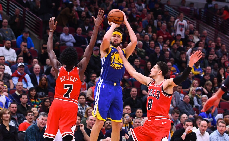 Golden State Warriors guard Klay Thompson shoots the ball against Chicago Bulls forward Justin Holiday (7) and guard Zach LaVine (8) during Monday night's game. Thompson broke the NBA's single-game record for 3-pointers.