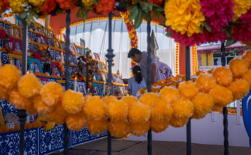 A father and daughter walk through the Day of the Dead altar in Tijuana's Mercado Hidalgo, October 22, 2025.