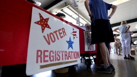 People stand near a voter registration table at a 2022 event in Fredericksburg, Texas.