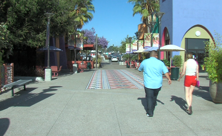 People walk on the mosaic of tiles at Market Creek Plaza.