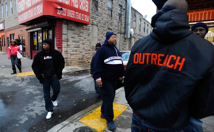 Workers for the Safe Streets violence interruption project including Gardnel Carter, center, talk with Baltimore residents in 2010.