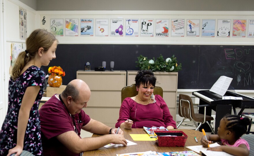 Erikka Wilkins (left), 12, waits for her father Carl Wilkins (seated) before heading home, as Katrina Vowell (center) jokes with Joyous Austin, 5.