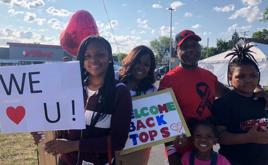 LeCandice Durham, Lenny Lane and their children stand by the Tops parking lot entrance in Buffalo, N.Y., on Friday to welcome back customers and employees on opening day after the supermarket was closed after May's mass shooting.