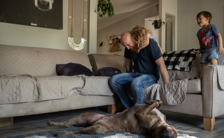 Wade Hanicker experiences hip pain while trying to give Nova Hanicker, 3, a piggy back ride while Cash Hanicker, 4, watches. He says the thing that affects him most is he cannot be the father he always pictured he would be. He can't run with his children. He gets tired very easily.