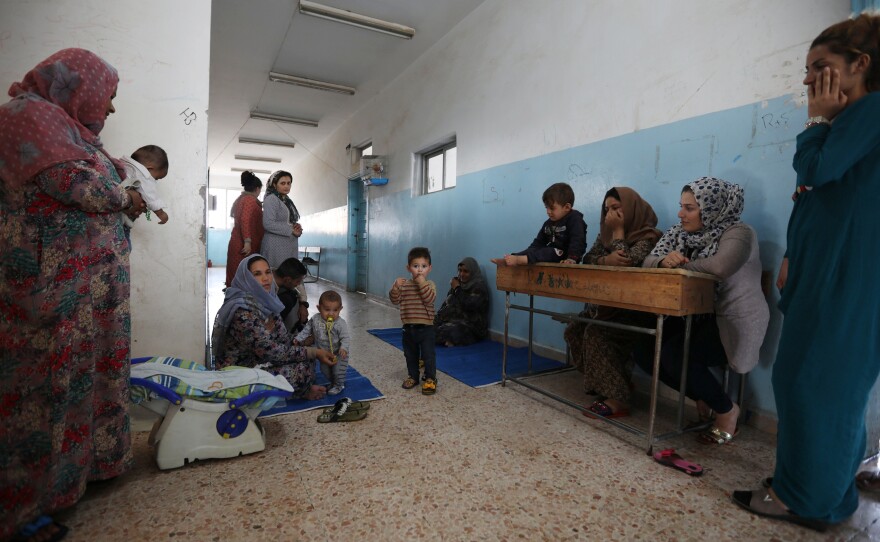 Displaced Kurdish and Arab women, who fled from violence after a Turkish offensive in northeastern Syria, sit with their children at a public school used as shelter where they now live in Hasakah, Syria.