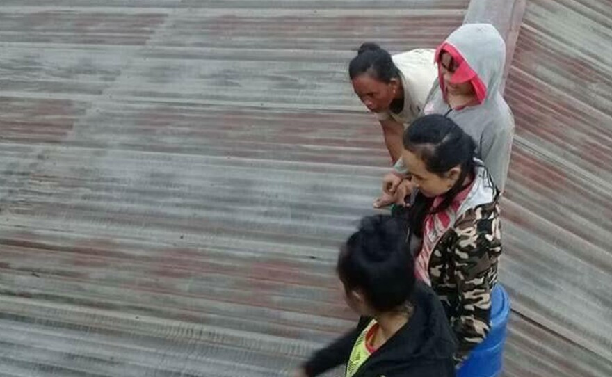 Villagers take refuge on a rooftop above floodwaters from a collapsed dam in southeastern Laos on Tuesday after a newly built hydroelectric dam was breached in southeastern Laos.