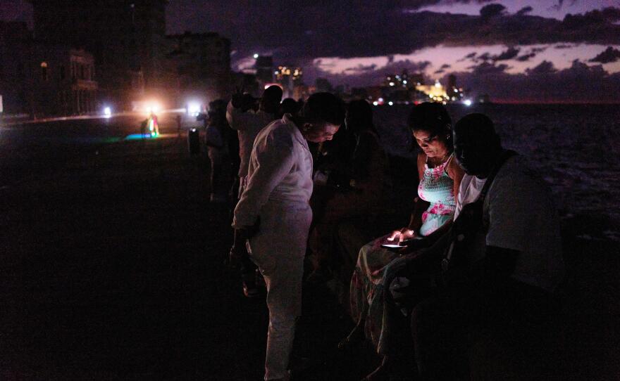 People spend the night in the dark on the Malecon during a blackout in Havana, Cuba, Saturday, March 21, 2026.