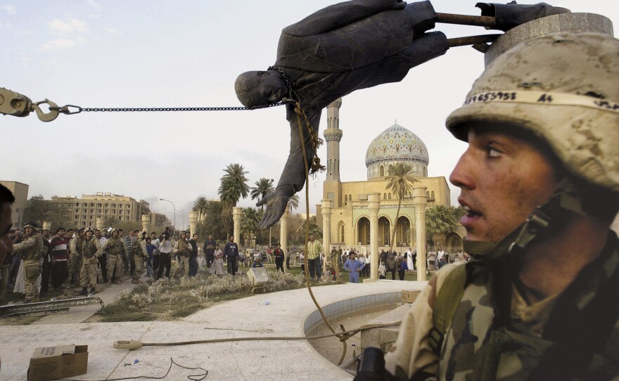Iraqi civilians and U.S. soldiers pull down a statue of Saddam Hussein in downtown Baghdad, April 9, 2003.